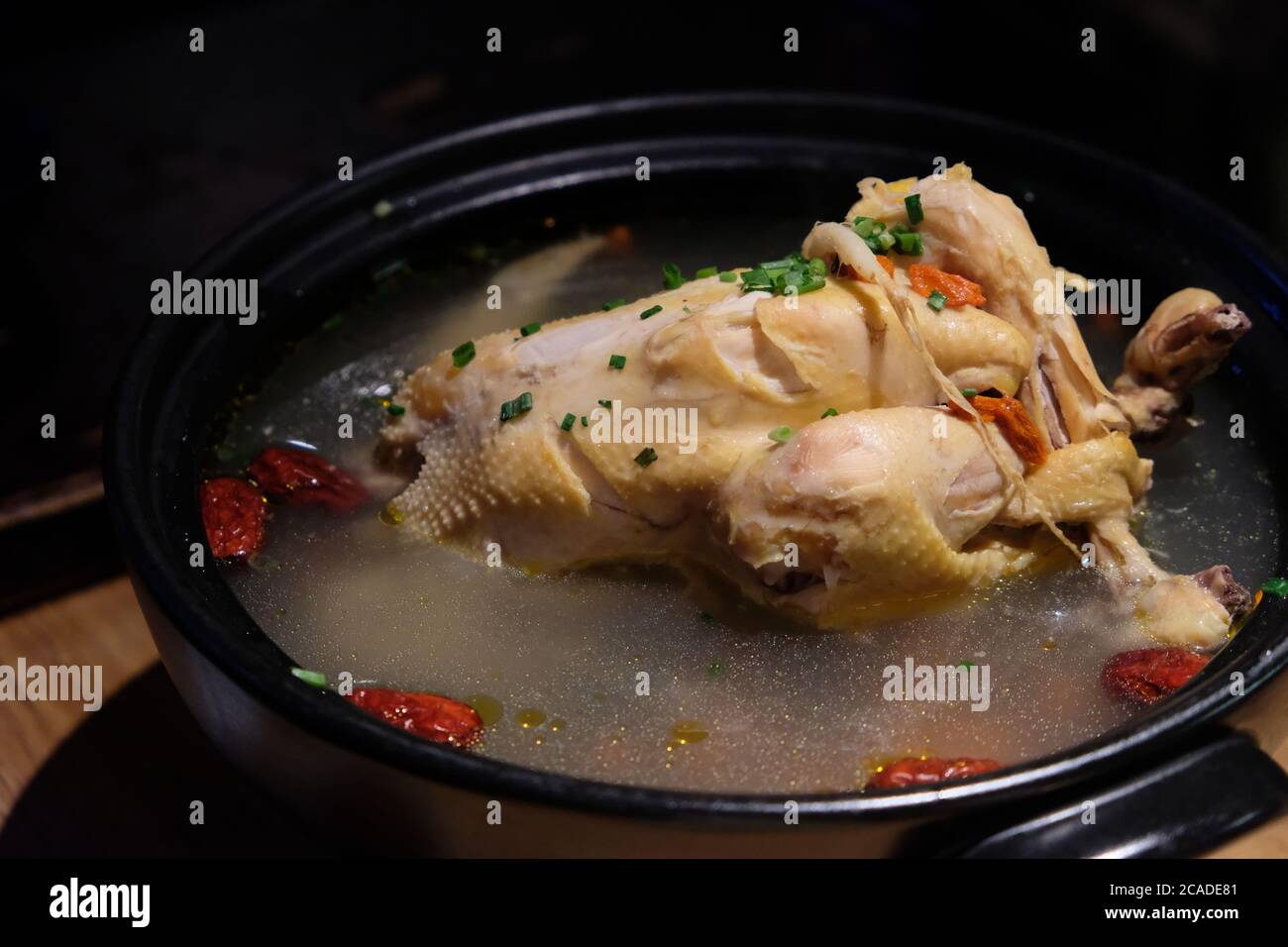 Gros plan sur la soupe de poulet au ginseng dans un pot noir. Cuisine traditionnelle en Chine et en Corée. Arrière-plan sombre flou Banque D'Images