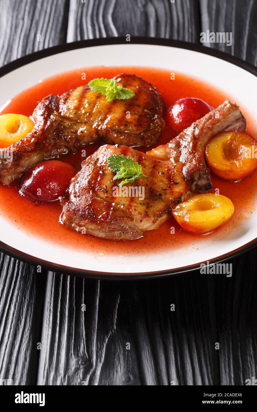 hacher le porc grillé avec une sauce aux prunes fraîche et à la menthe dans une assiette sur la table. verticale Banque D'Images