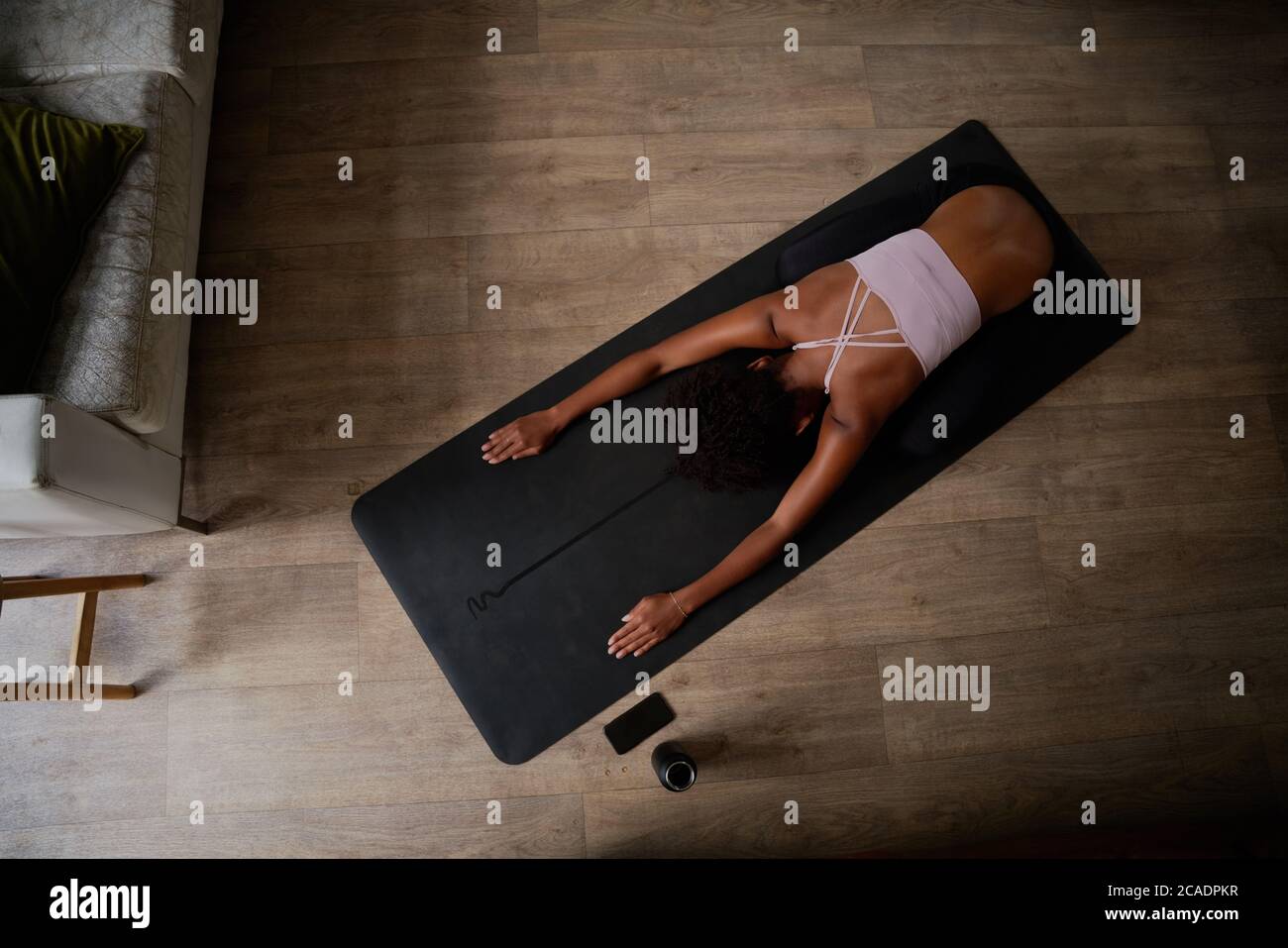 Vue en grand angle d'une jeune femme assise sur un tapis de yoga qui fait de l'exercice d'étirement Banque D'Images