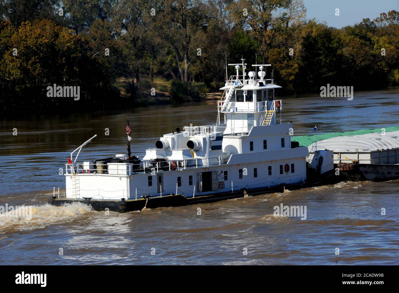 Le bateau à remorqueurs, également appelé un pousseur, fait ses muscles jusqu'au fleuve Mississippi en Arkansas. Le bateau est blanc. Banque D'Images