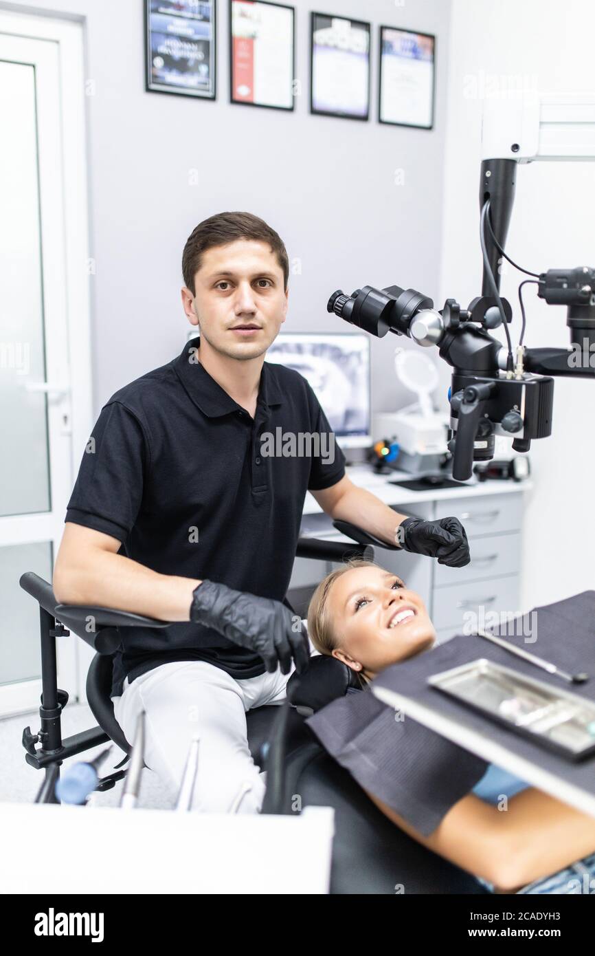 Nous améliorons votre sourire. Dentiste masculin observez le patient à l'aide d'un microscope binoculaire dentaire professionnel. Banque D'Images