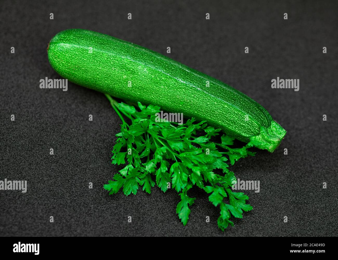 Courgettes et persil sur fond sombre Banque D'Images