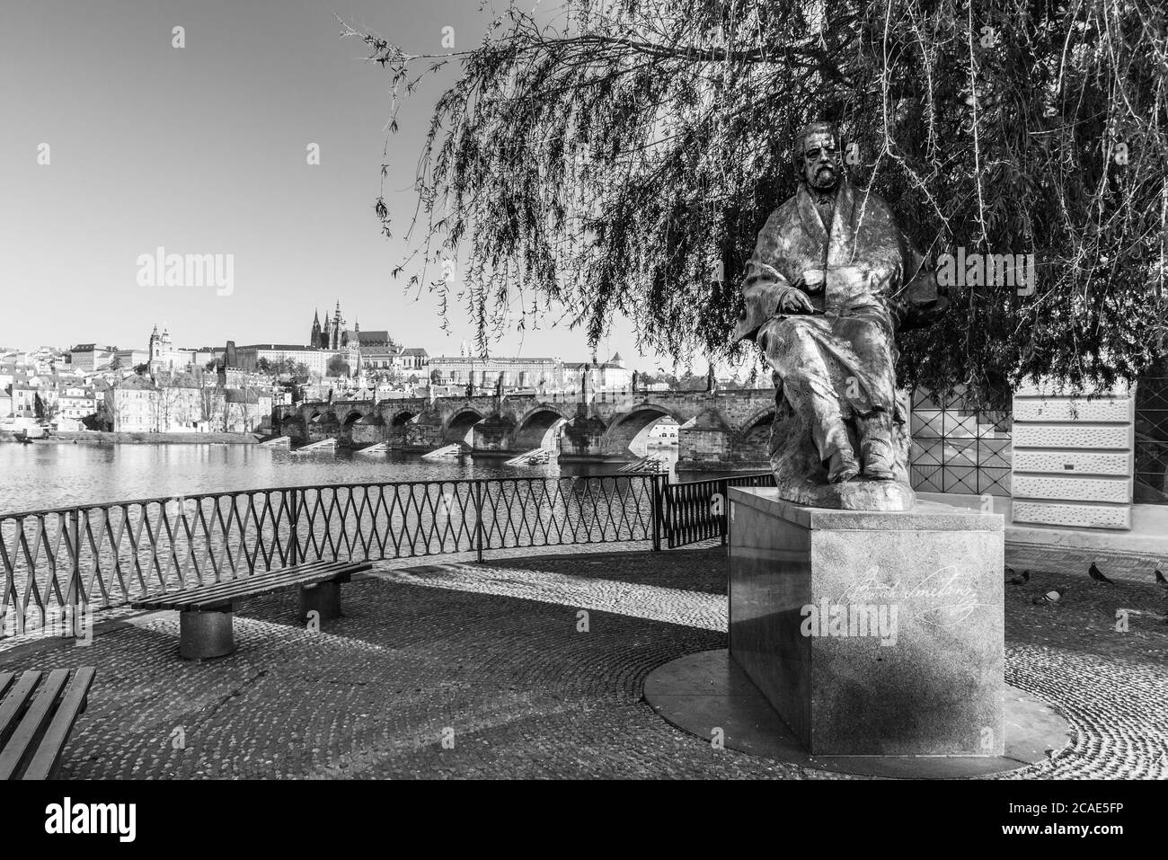 Statue de Bedrich Smetana, compositeur tchèque, au pont de pied de Novotny. Avec vue panoramique sur la Vltava, le pont Charles et le château de Prague en arrière-plan. Praha, République tchèque. Image en noir et blanc. Banque D'Images