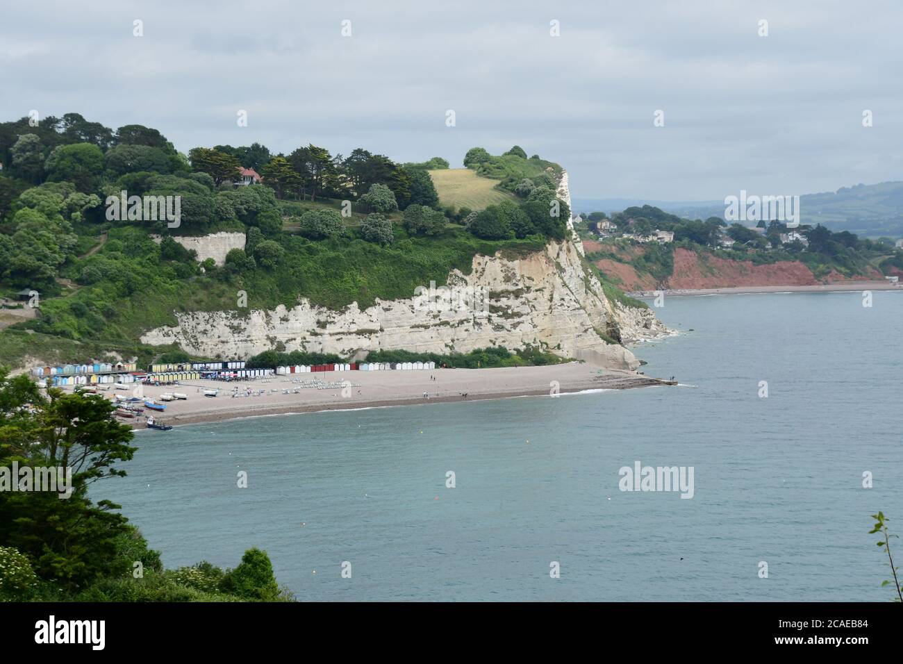 La plage colorée s'étend sur la plage de galets au village de pêcheurs de Beer à Devon, éclipsé par la falaise de craie, une intrusion dans le sable rouge Banque D'Images