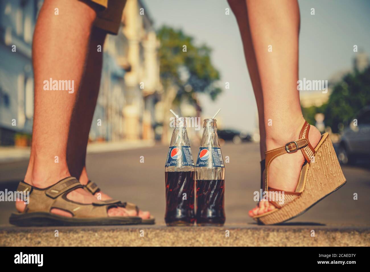 ODESSA, UKRAINE - 15 OCTOBRE 2014 : gros plan des pieds de la femme debout sur le tiptep tout en embrassant avec l'homme à l'extérieur en été. Pepsi en bouteilles de verre avec Banque D'Images