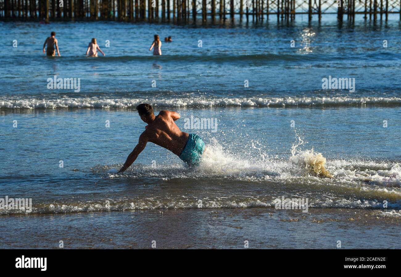 Brighton UK 6 août 2020 - ce jeune homme aime glisser dans la mer sur la plage de Brighton lors d'une belle soirée ensoleillée comme les températures devraient atteindre plus de 30 degrés dans le Sud-est de nouveau demain : crédit Simon Dack / Alay Live News Banque D'Images