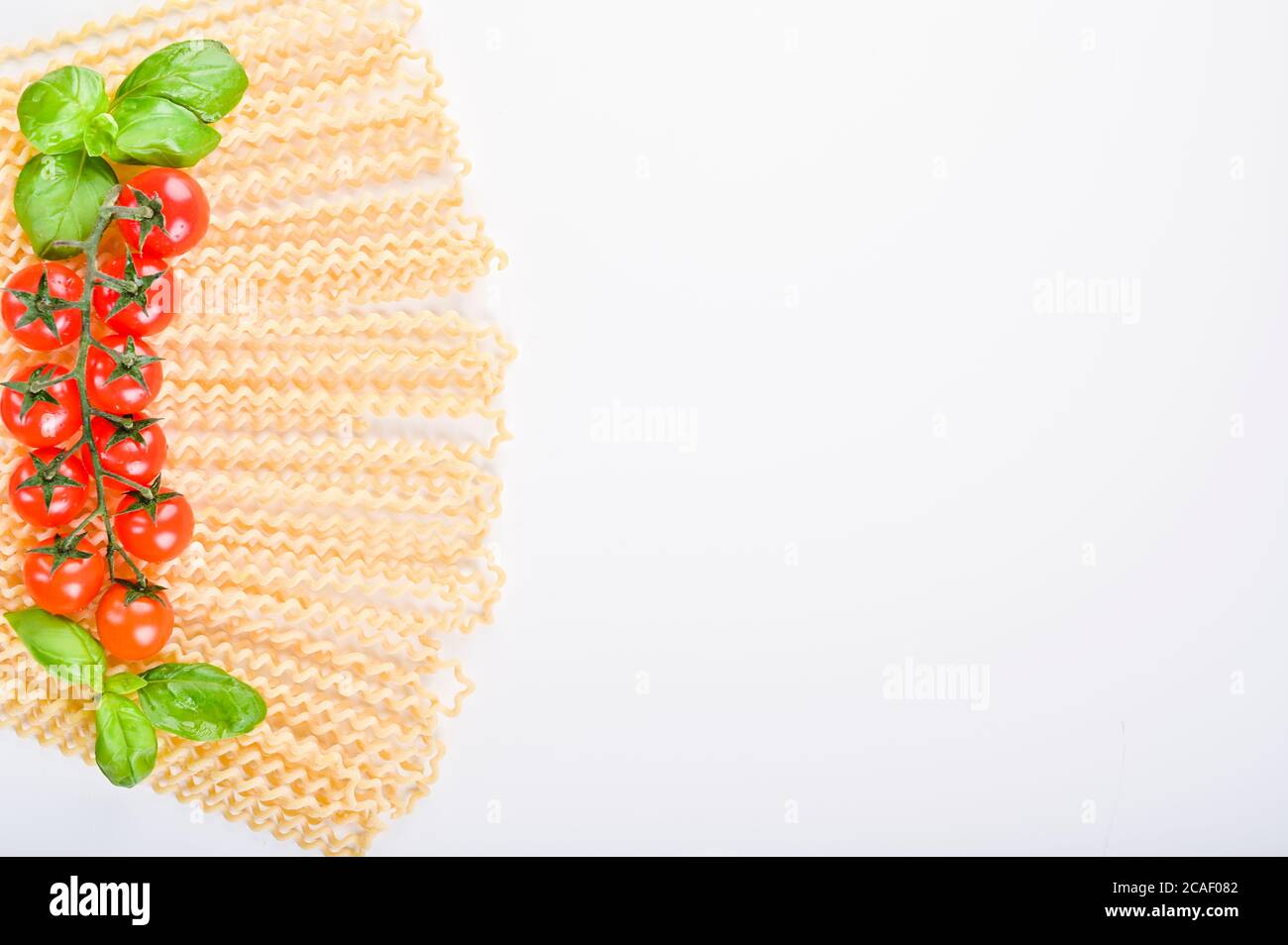 Fusilli lunghi bucati . Pâtes longues au curly sur une assiette blanche, avec des feuilles de basilic frais et des tomates cerises. Pâtes italiennes traditionnelles du sud. Photo de haute qualité. Copier l'espace Banque D'Images