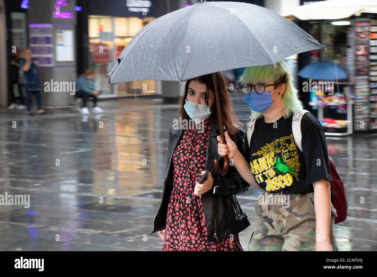 Belgrade, Serbie - 5 août 2020 : deux jeunes femmes portant des masques chirurgicaux et un costume de mode grunge coloré de style de rue marchant sous des parasols Banque D'Images