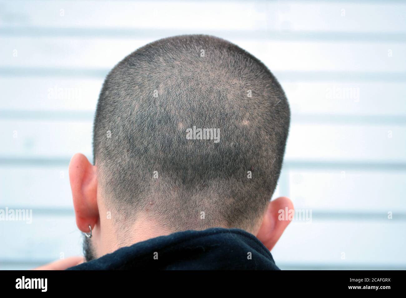 Gros plan sur le dos de la tête du jeune homme. L'homme a une coupe de  bourdonnement et porte des boucles d'oreilles Photo Stock - Alamy