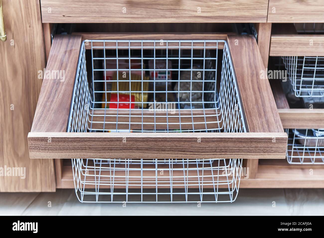 Organisation du stockage. Panier en maille métallique dans un tiroir en bois dans la salle de stockage des aliments. Gros plan Banque D'Images