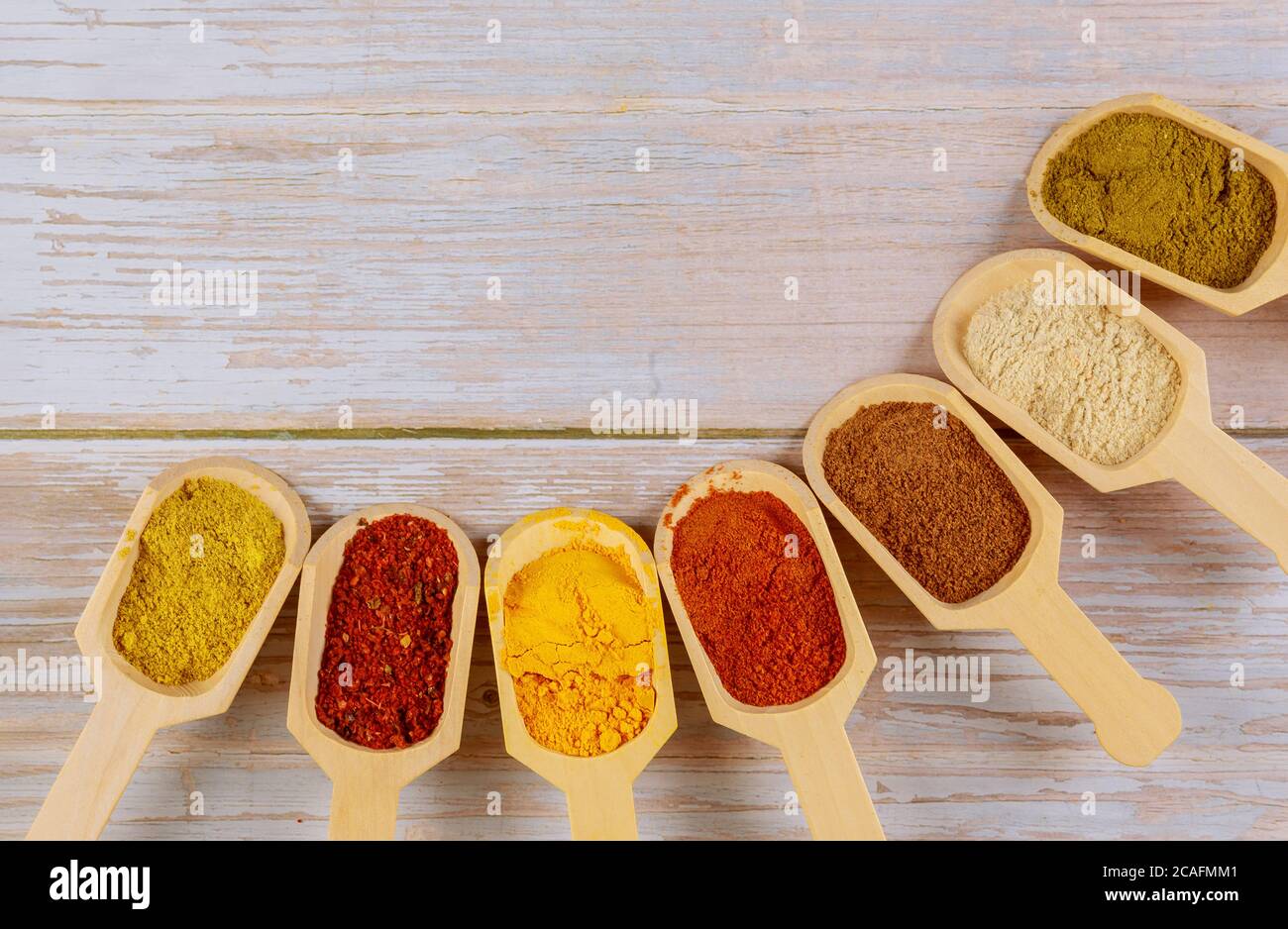 Assortiment d'épices colorées dans les cuillères en bois sur fond de bois. Banque D'Images