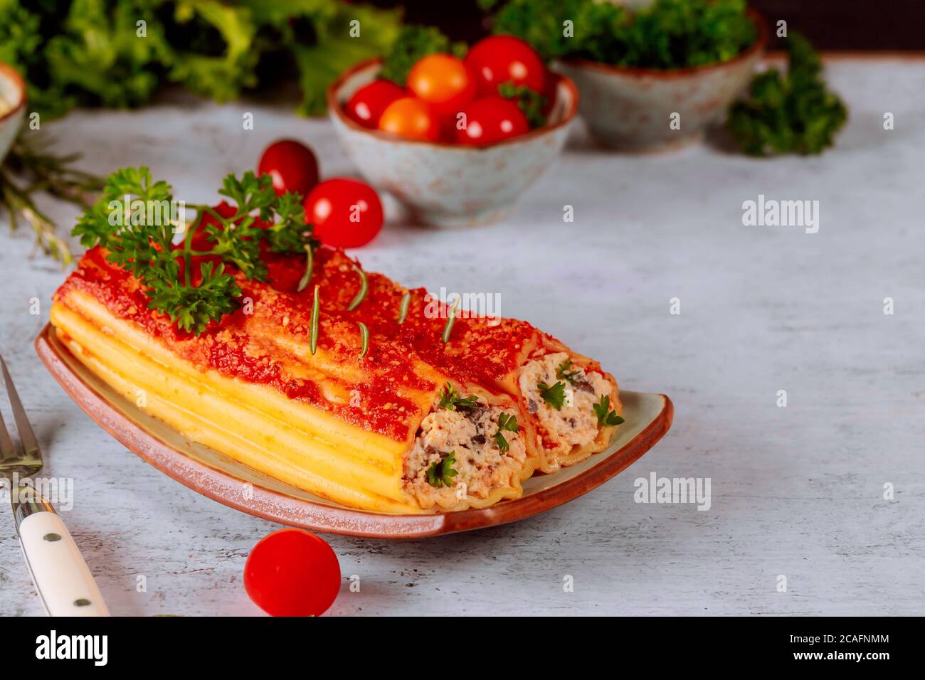 Pâtes Jumbo cannelloni sur plaque avec tomates cerises. Banque D'Images