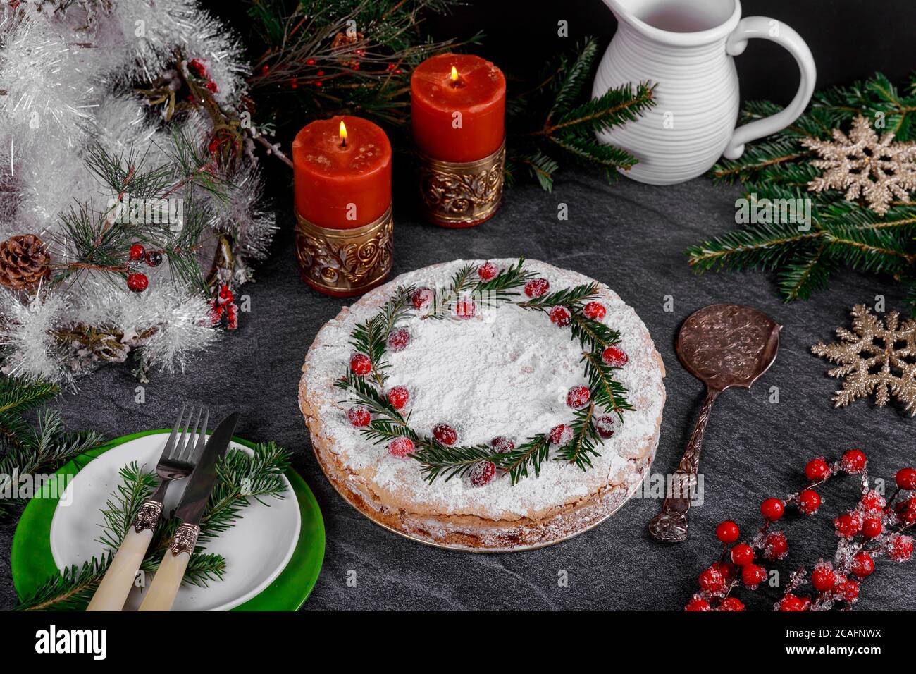 Tarte festive de vacances avec décoration cranibarry sur table noire avec bougies allumées et branches de pin. Banque D'Images