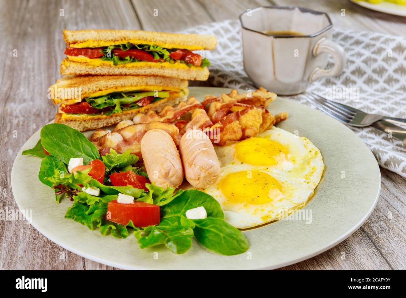 Petitdéjeuner anglais traditionnel avec bacon, œufs, saucisses, salade et pain grillé au