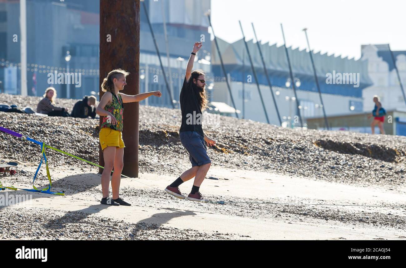 Brighton Royaume-Uni 7 août 2020 - ce couple essaie de garder leur équilibre sur une corde raide qu'ils ont mis en place par Brighton's West Pier sur une belle matinée chaude et ensoleillée que la température est prévue pour atteindre les 30s élevés dans certaines parties du Sud-est : Credit Simon Dack / Alamy Live News Banque D'Images