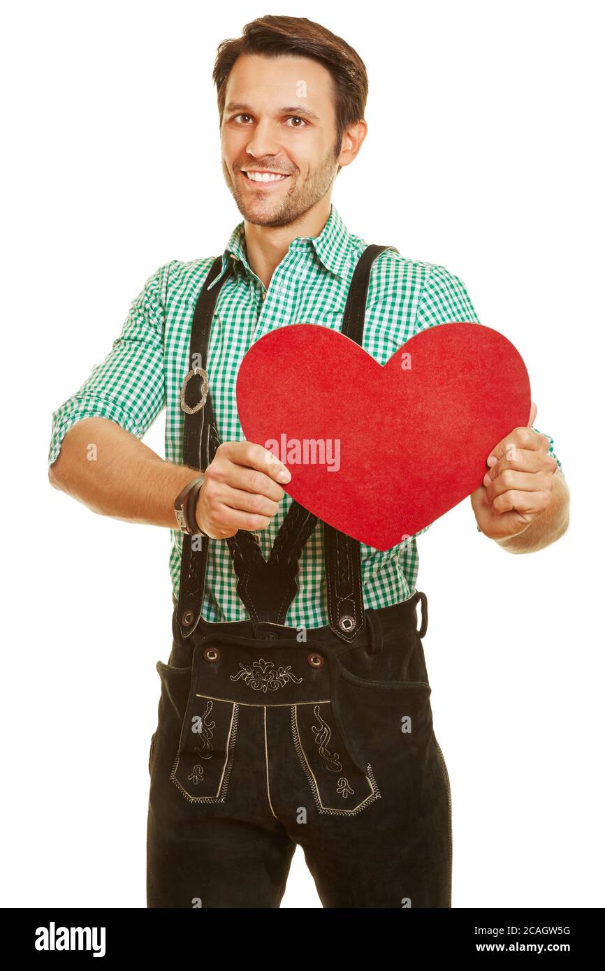 Homme souriant dans un pantalon en cuir tient un grand coeur rouge Banque D'Images