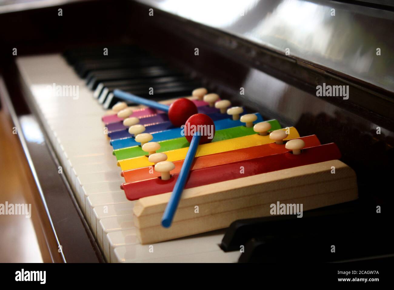 Gros plan d'un jouet xylophone coloré avec des maillets mis sur le clavier d'un piano classique. Banque D'Images