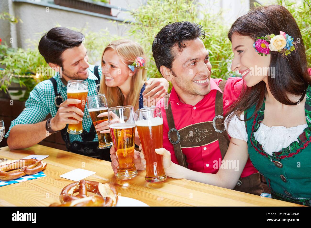 Deux couples en train de rire boivent de la bière ensemble dans le café en plein air Banque D'Images