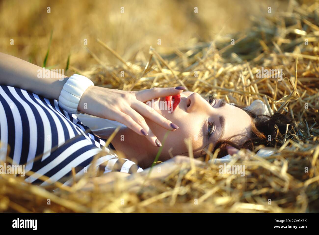 belle fille dans une robe rayée posant dans l'été dans le champ Banque D'Images