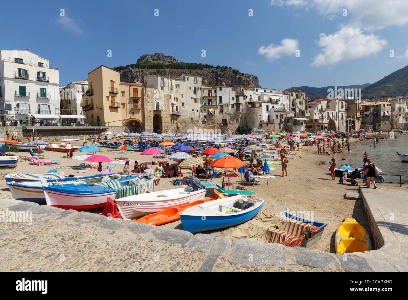 11.08.2018, Cefalu, Sicile, Italie - les bateaux de pêche sont amarrés à la plage de la ville. En arrière-plan, maisons de la vieille ville, surplombées par le calcaire Banque D'Images