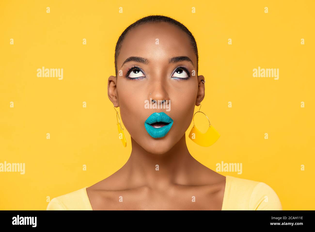 Gros plan de la belle jeune femme afro-américaine avec tendance et coloré maquillage isolé sur fond jaune studio Banque D'Images