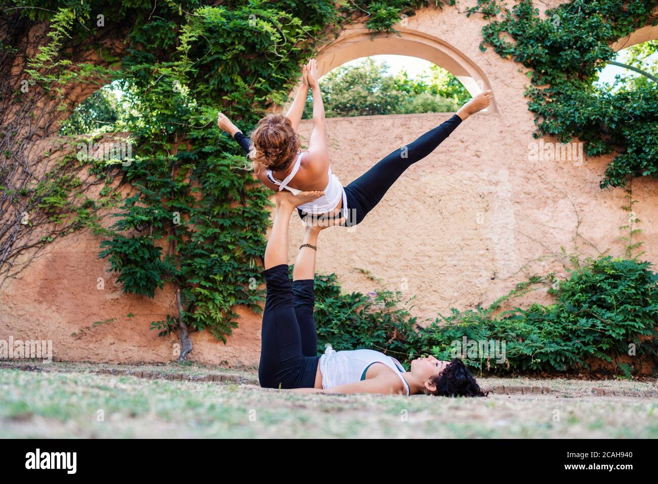 Deux belles femmes faisant acroyoga dans le jardin ou le parc Banque D'Images