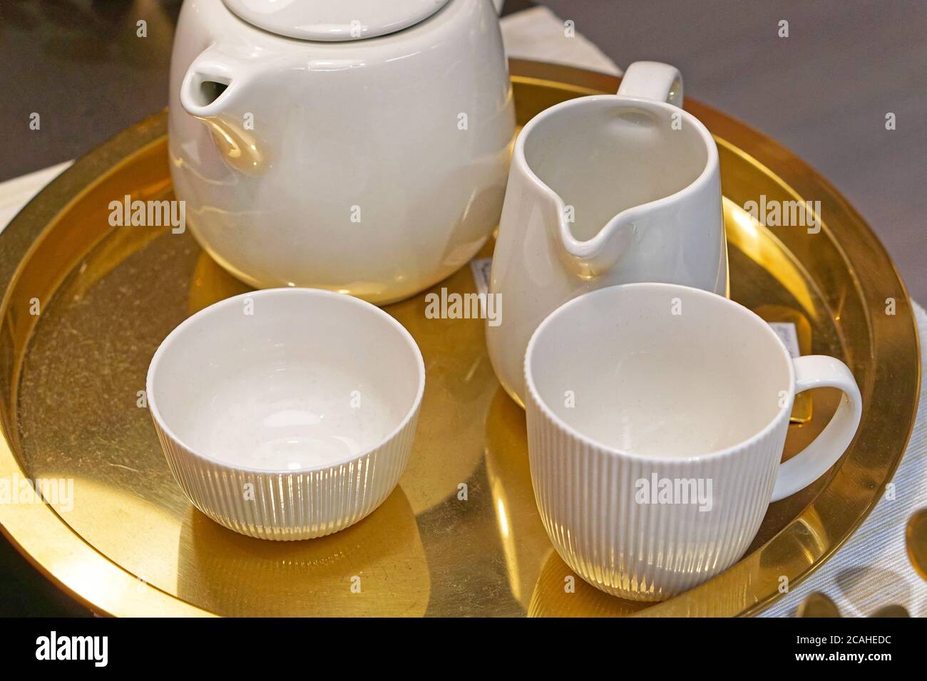 Ensemble de thé en céramique en porcelaine blanche sur plateau doré Banque D'Images