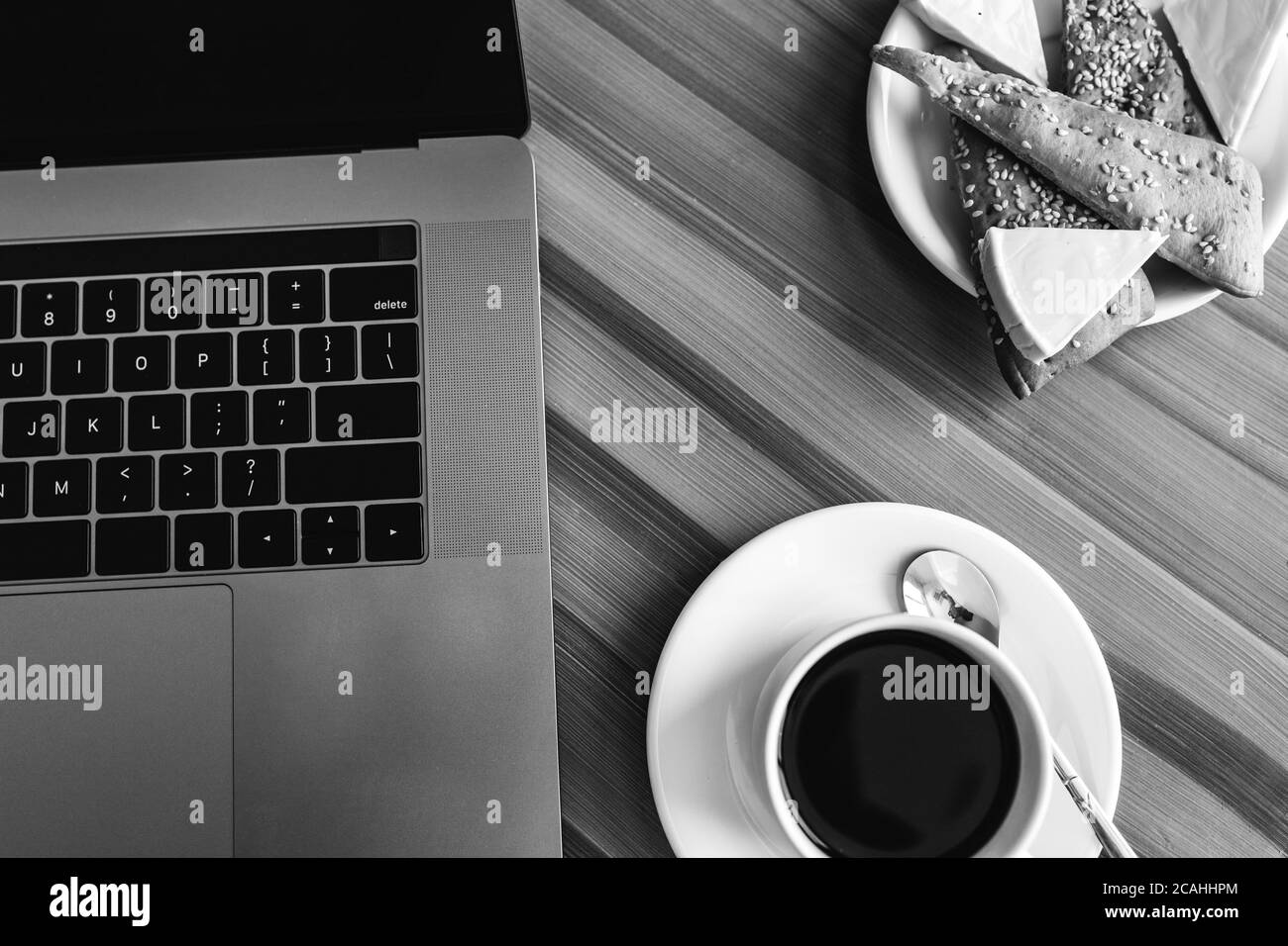Photo en noir et blanc. Vue sur un espace de travail avec un ordinateur portable sur une table en bois, avec une tasse de café. Concept de pause. Copier l'espace Banque D'Images