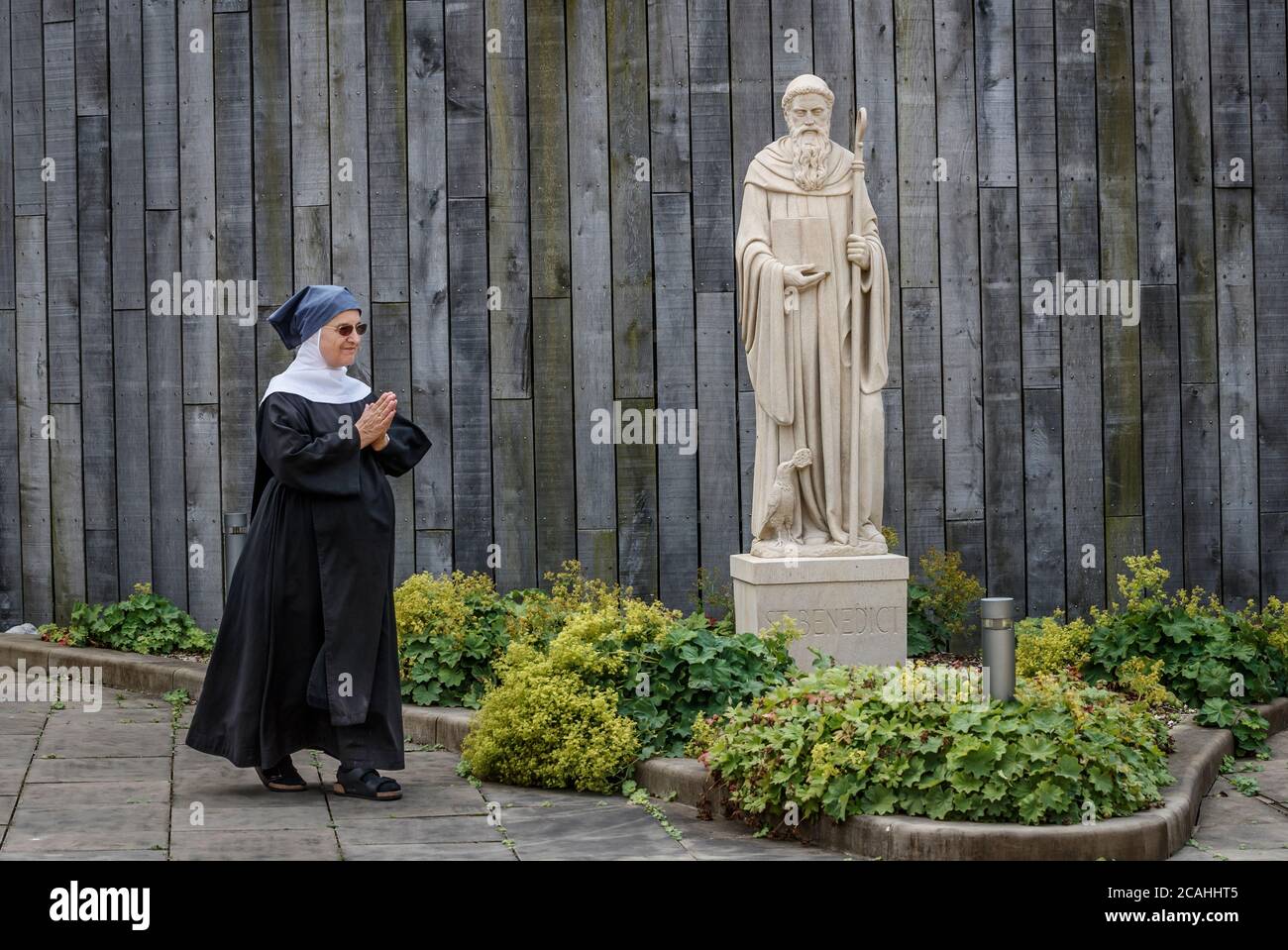 Sœur Agnes passe devant une statue de Saint Benoît récemment installée à la nionnerie de l'abbaye de Stanbrook à Wass, dans le North Yorkshire. La statue, réalisée par Matthias Garn Master Mason et Partner à partir d'un seul morceau de grès à grain fin du West Yorkshire, est une réplique d'une statue existante qui a été gravement abîmé en raison du climat rigoureux de l'abbaye de Stanbrook. Banque D'Images