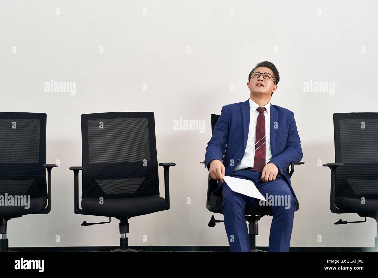 un homme asiatique plus âgé recherche un emploi à la hauteur du plafond en attendant une interview Banque D'Images