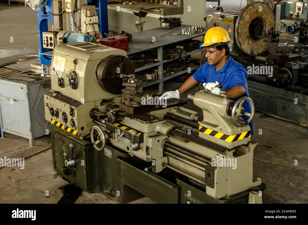 Ligne de production de métal de tournage. Travailleur préparant la machine à travailler. Banque D'Images