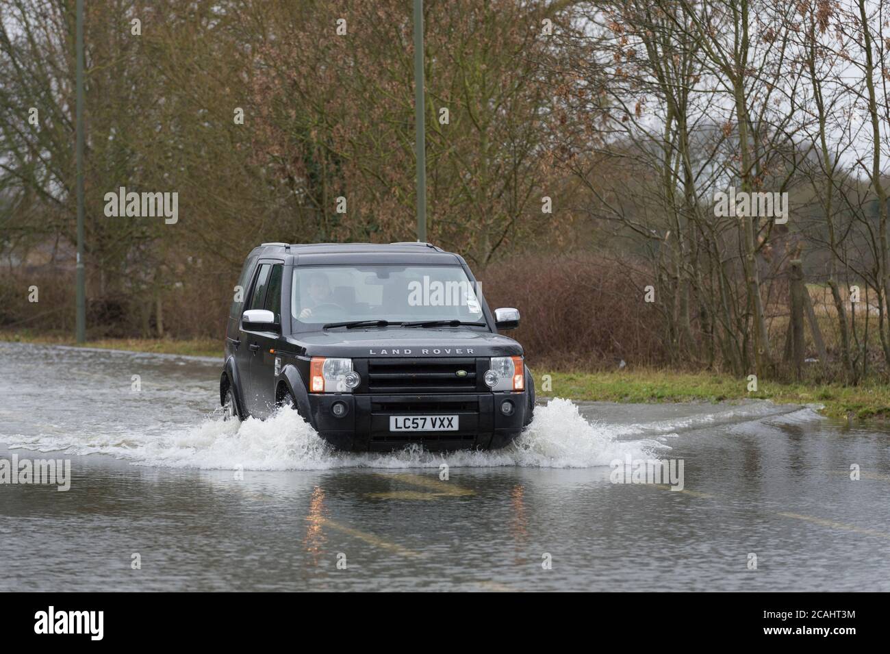 Une voiture qui traverse les eaux d'inondation de Chertsey Lane, Egham Hythe, Surrey, après que la Tamise a brisé les berges, Chertsey Lane, Egham Hythe, Surrey, Royaume-Uni. 14 févr. 2014 Banque D'Images