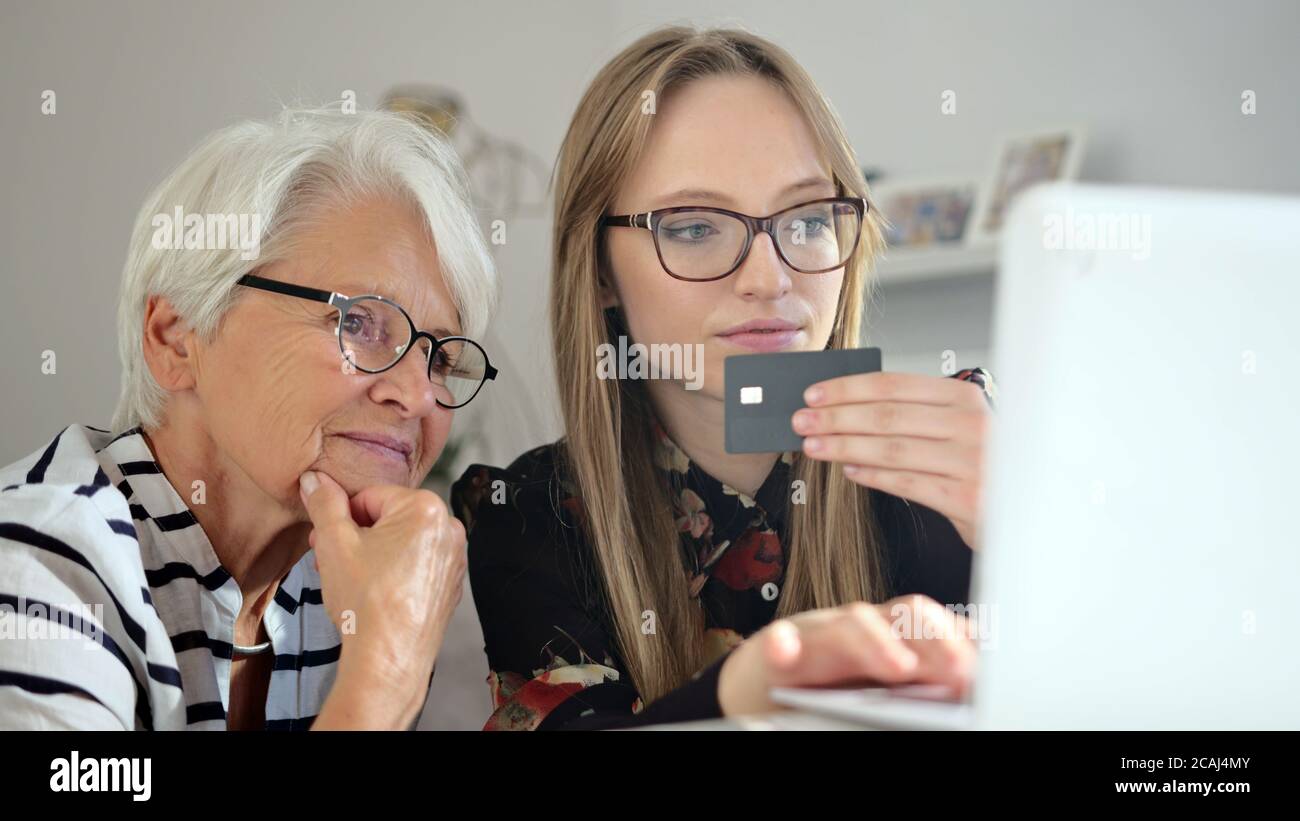 Petite-fille aidant sa grand-mère à faire des achats en ligne. Commande de produits en ligne. Vidéos 4k de haute qualité Banque D'Images