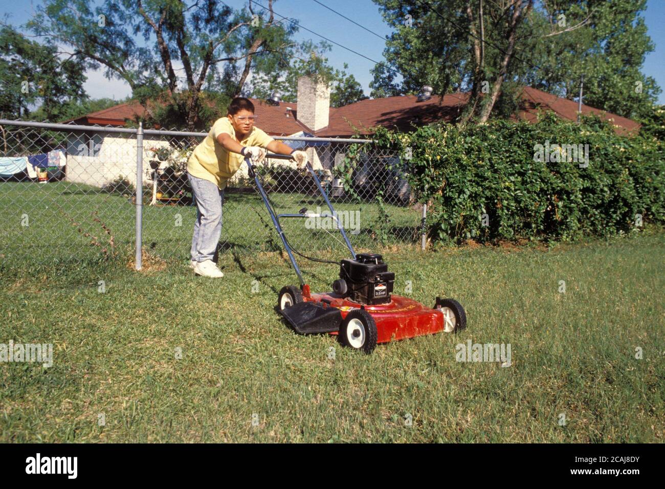 Austin, Texas USA,1988: Hispanique garçon, 13 ans, tonte de pelouse avec une tondeuse à gaz. M. RR-0092. ©Bob Daemmrich Banque D'Images