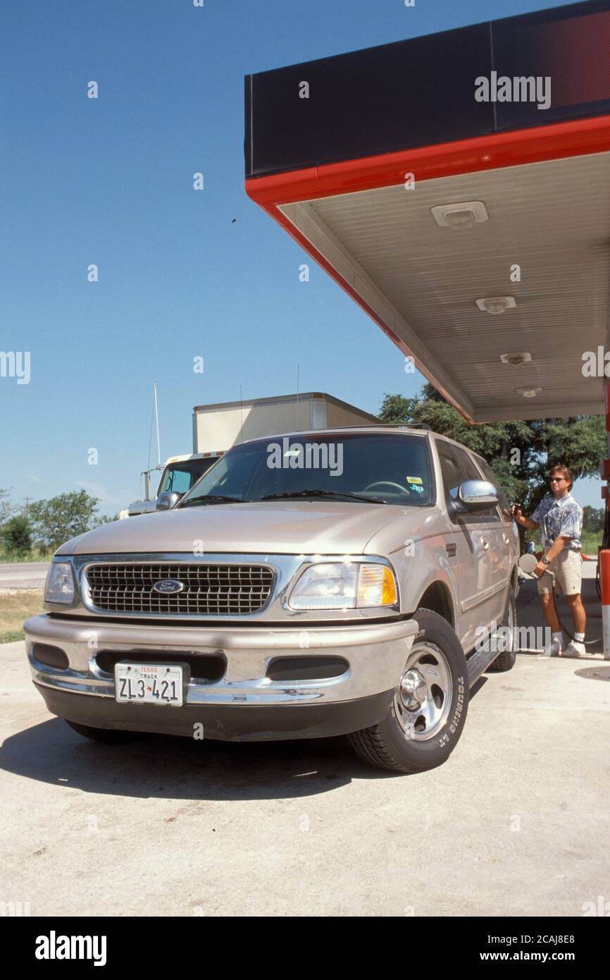 Homme qui fait le plein d'essence d'un véhicule utilitaire sport à la station-service. Autorisation du modèle ©Bob Daemmrich Banque D'Images