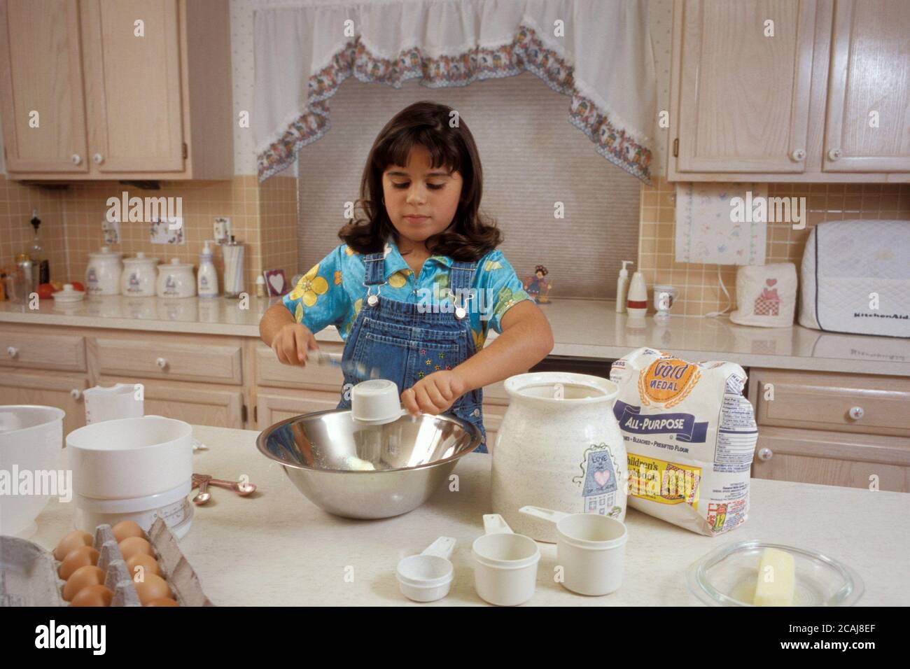 Austin, Texas USA, 1997: Fille panaméenne-américaine de huit ans mesurant des ingrédients de quart de tasse et demi de tasse dans un bol tout en aidant à cuire à la maison. M. ©Bob Daemmrich Banque D'Images