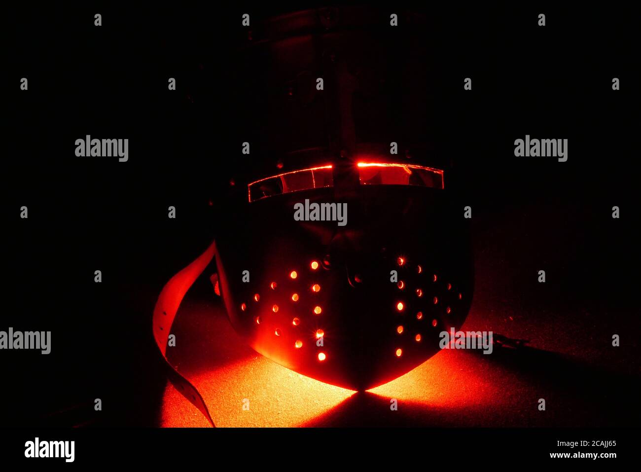 Casque médiéval dans l'obscurité avec une lueur rouge sinistre 1 Banque D'Images