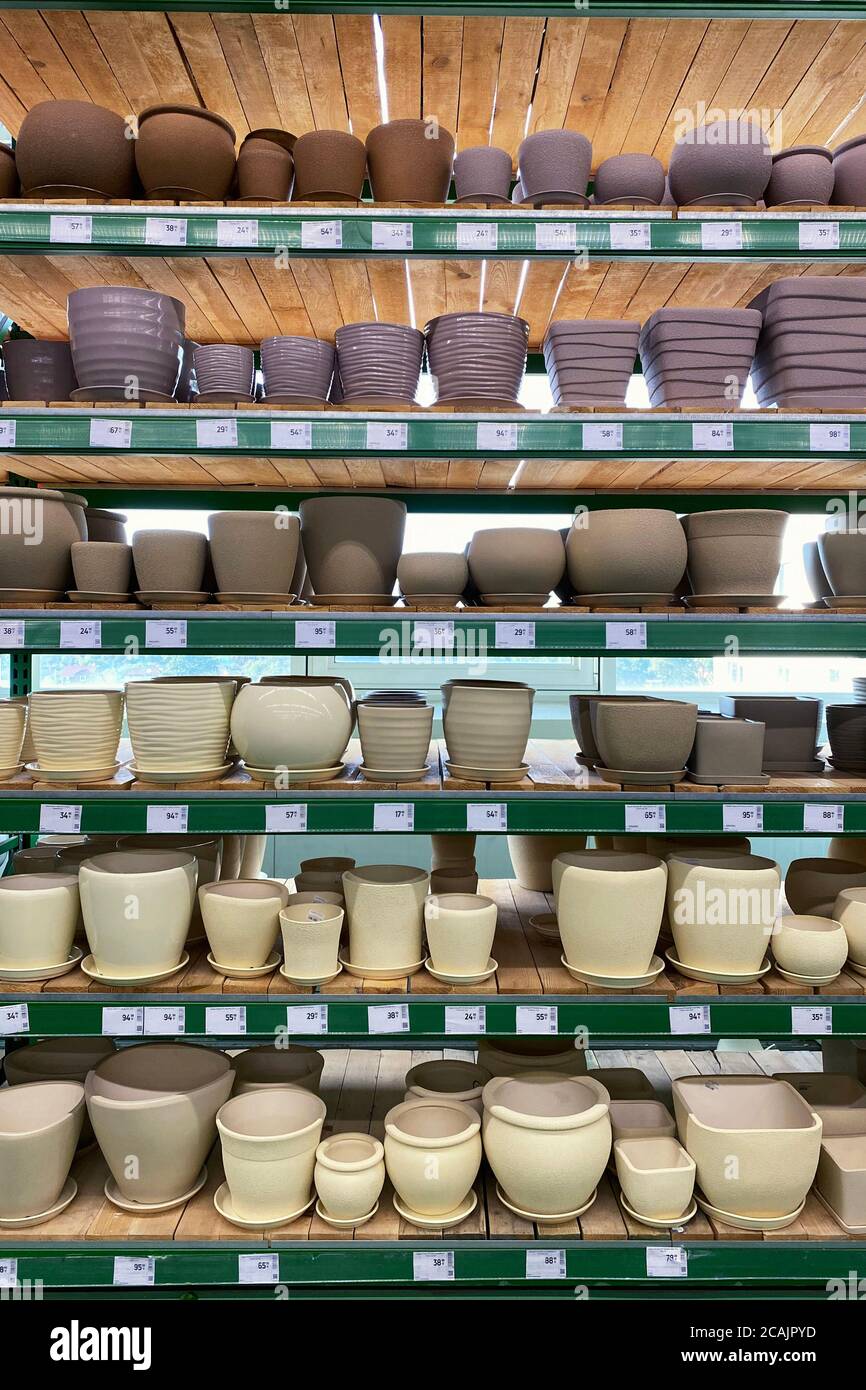 Les pots de fleurs sont vendus au magasin. Rangées de différents pots beiges et violets pour plantes d'intérieur sur des étagères dans un supermarché. Vue verticale. Banque D'Images