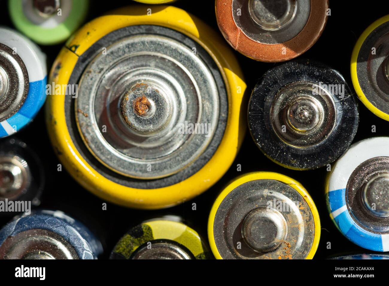 Gros plan des extrémités positives des batteries déchargées de différentes tailles et formats, mise au point sélective. Batterie usagée corrodée et rouillée. Risque d'accident Banque D'Images