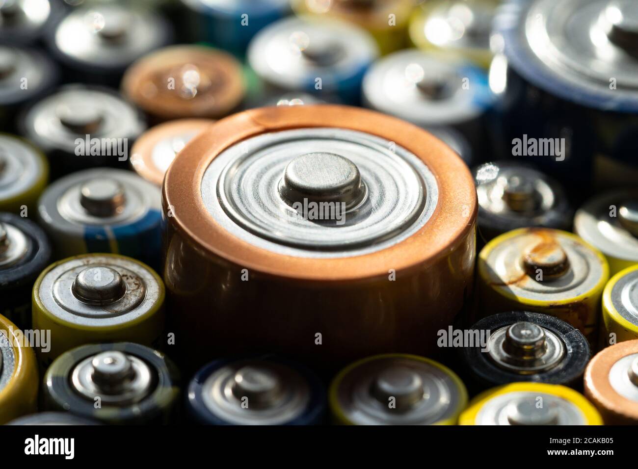 Gros plan des extrémités positives des batteries déchargées de différentes tailles et formats, mise au point sélective. Pile alcaline usagée. Notion : déchets dangereux Banque D'Images