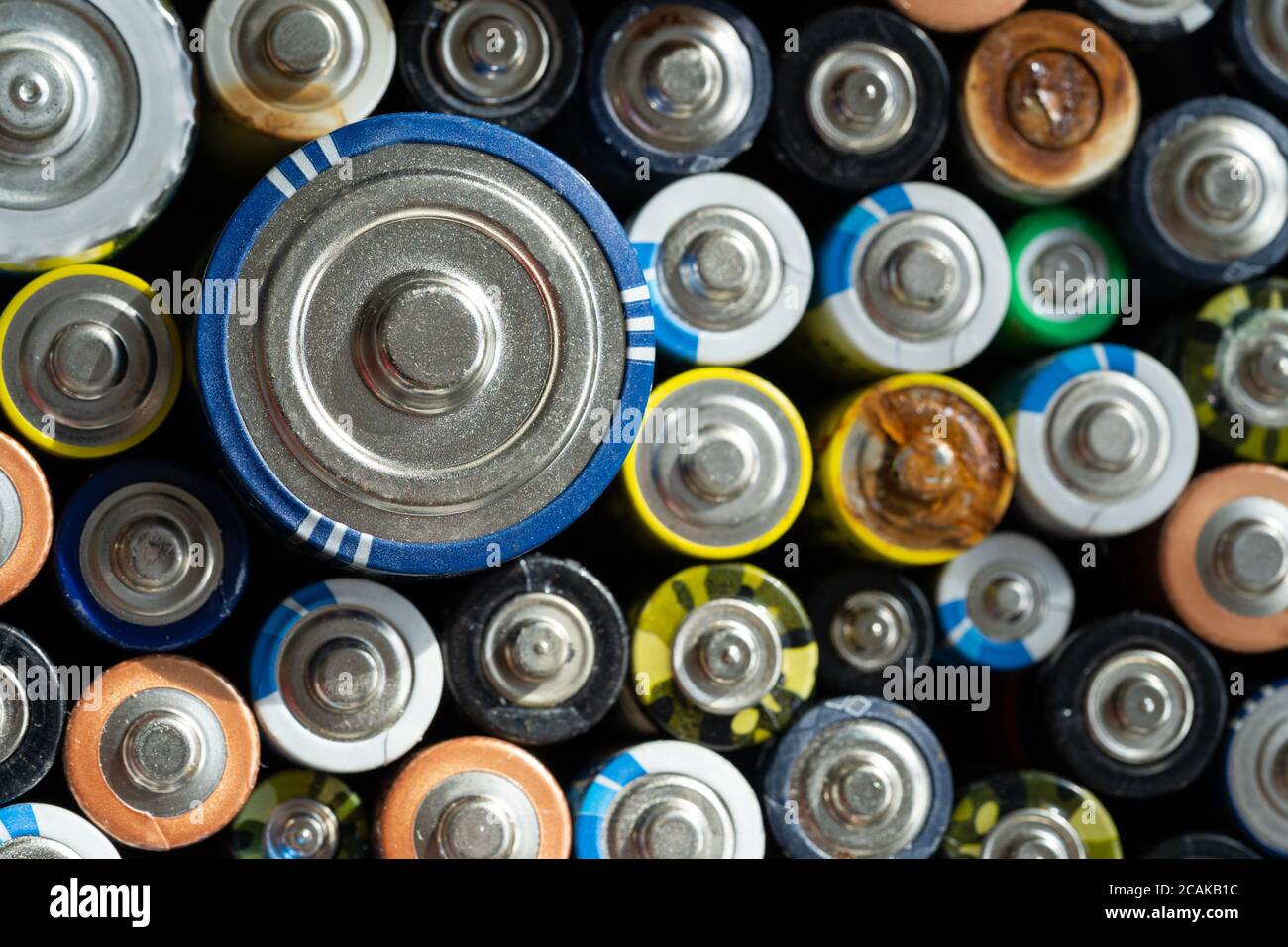 Gros plan des extrémités positives des batteries déchargées de différentes tailles et formats, mise au point sélective. Pile alcaline usagée corrodée et rouillée. Haza Banque D'Images