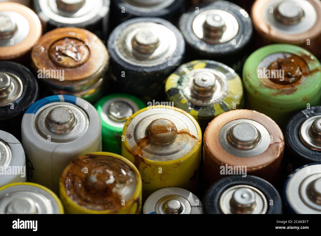Gros plan des extrémités positives des batteries déchargées de différentes tailles et formats, mise au point sélective. Batterie usagée corrodée et rouillée. Risque d'accident Banque D'Images
