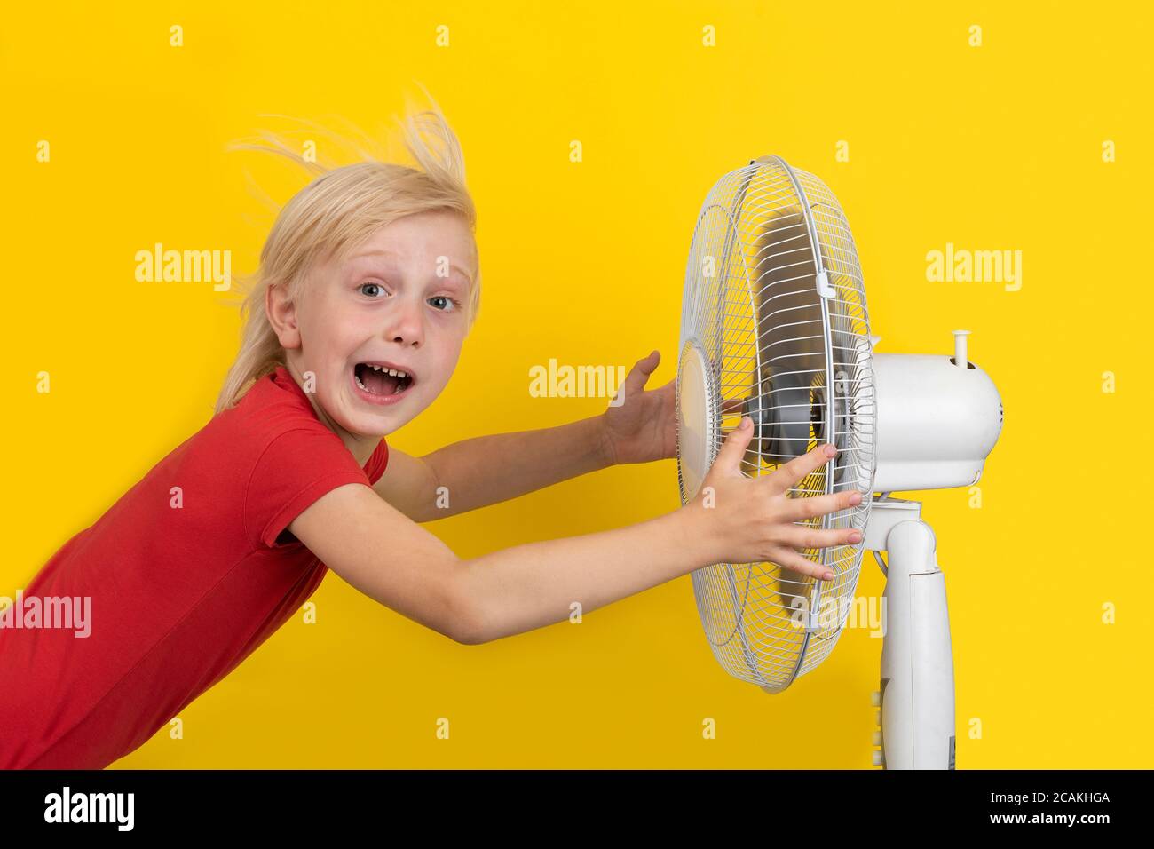 Garçon et ventilateur sur fond jaune. L'enfant refroidit avec le ventilateur.  Temps chaud Photo Stock - Alamy