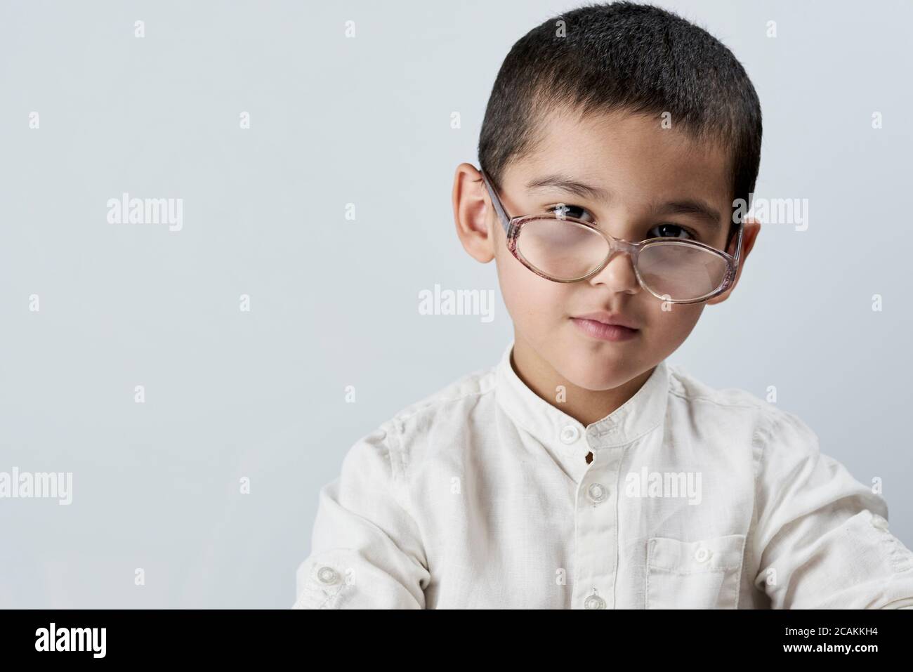 Portrait d'un garçon de course mixte de 7 ans regardant l'appareil photo. Un portrait élégant de garçon d'école sur fond blanc Banque D'Images