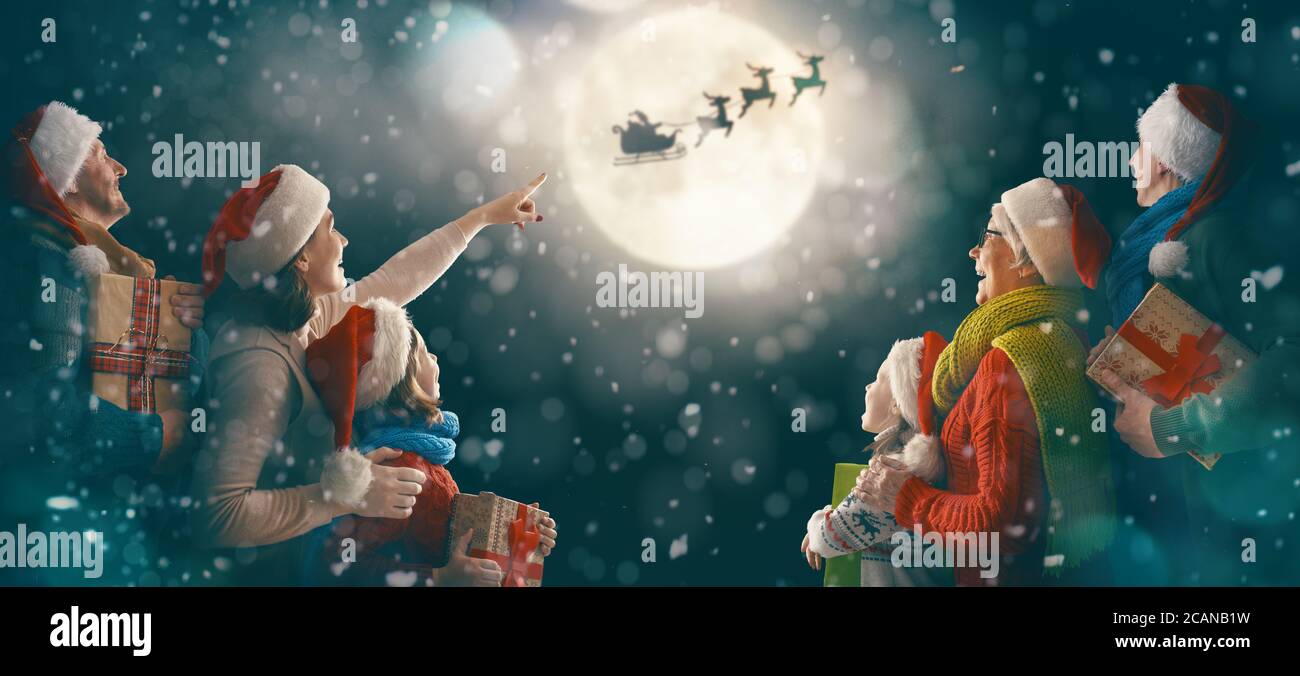 Joyeux Noel Et Joyeuses Fetes Petits Enfants Adorables Avec Maman Papa Grand Mere Et Grand Pere Le Pere Noel Vole Dans Son Traineau Contre Le Ciel Lunaire Famille Photo Stock Alamy
