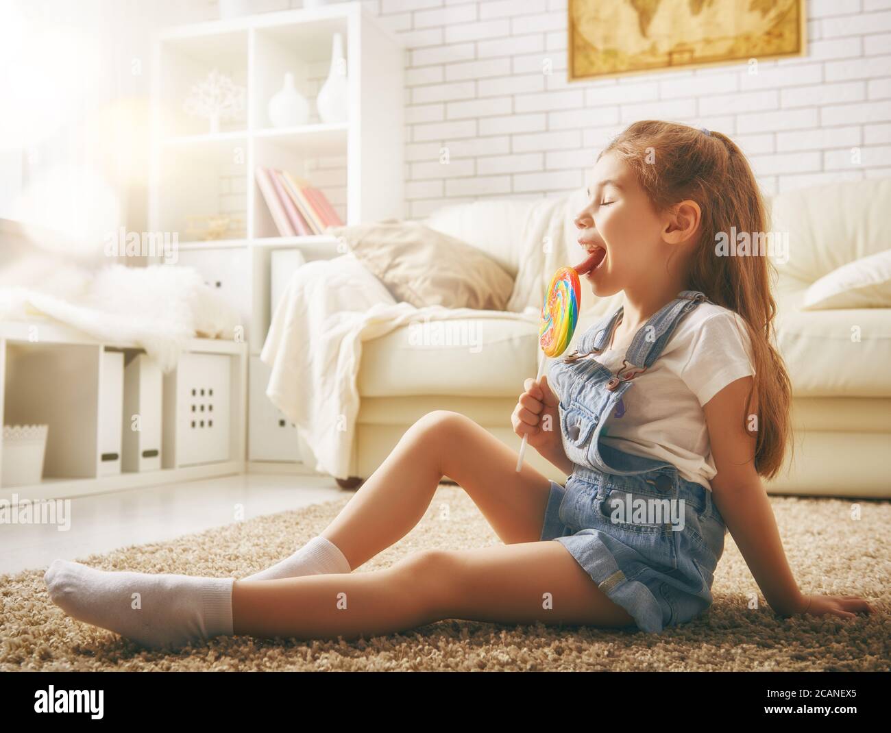 drôle enfant fille joue à la maison. fille mangeant des bonbons et de repos. loisirs et divertissement à la maison. Banque D'Images