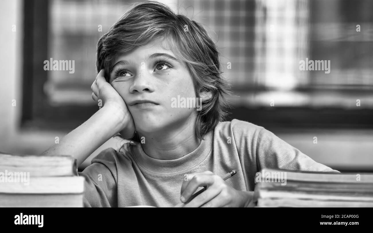 Un garçon caucasien dans la pensée en classe. Concept de retour à l'école. Banque D'Images