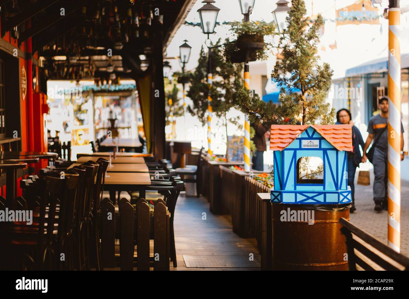 Une poubelle en forme de maison allemande, un lustre fait de bouteilles de bière, chaises et tables d'un restaurant vide à Vila Germanica, Blumenau - B. Banque D'Images