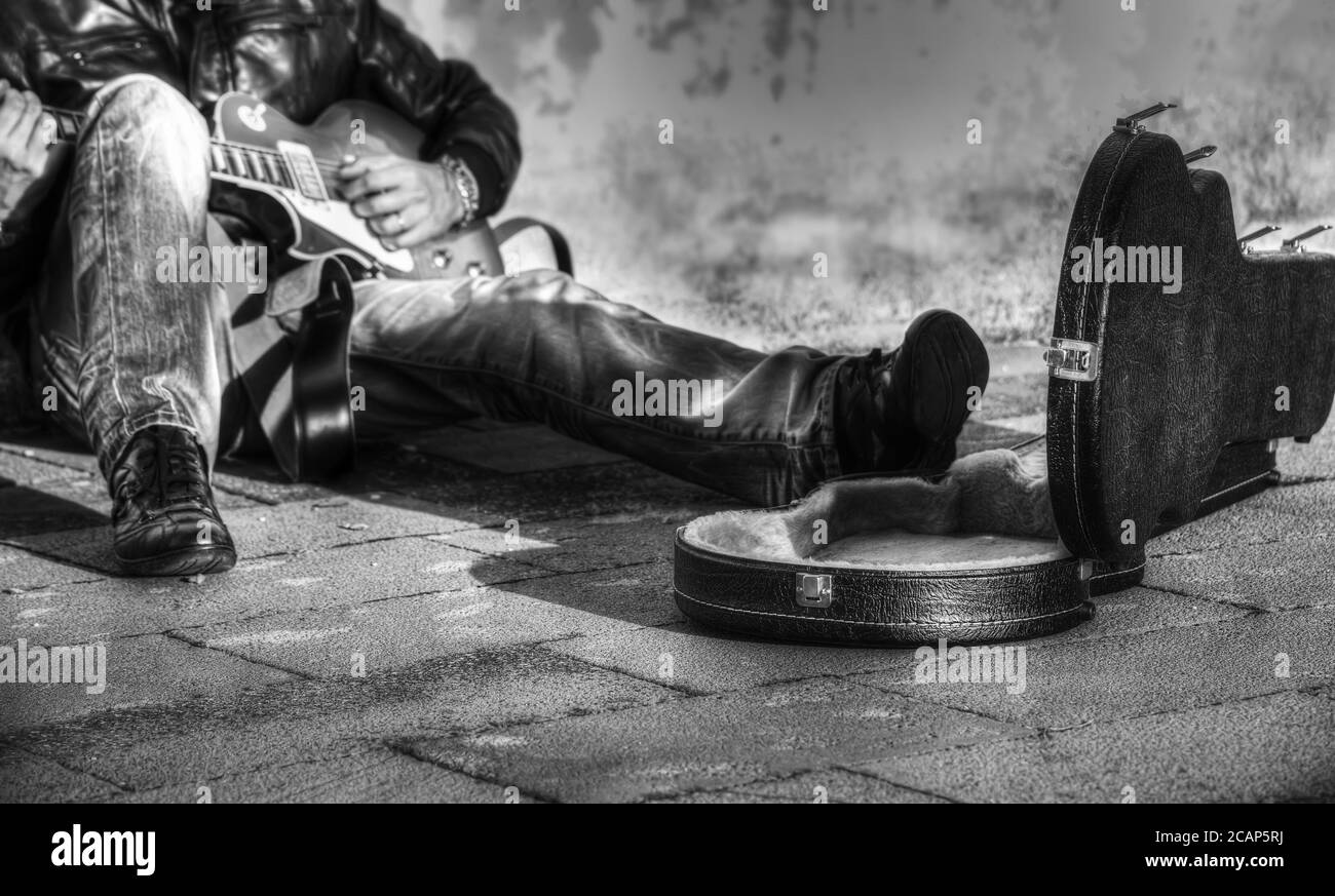 guitariste dans la rue avec un étui pour guitare ouvert en noir et blanc Banque D'Images