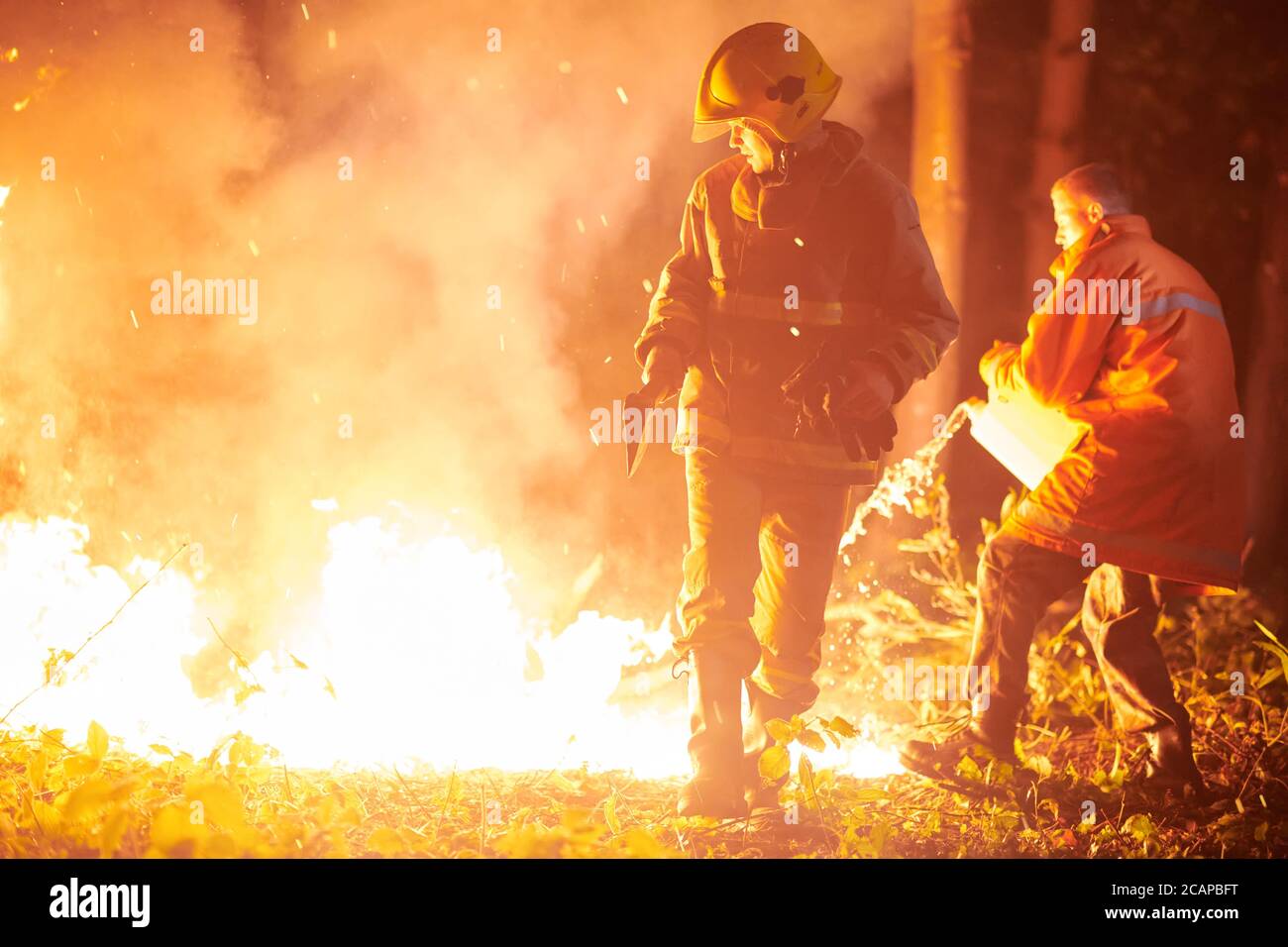 le héros du pompier en action risque de sauter au-dessus d'une flamme de feu pour sauver et sauver Banque D'Images